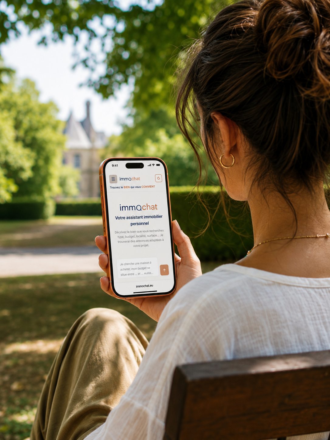 Une femme consulte ImmoChat depuis un parc, face à une maison